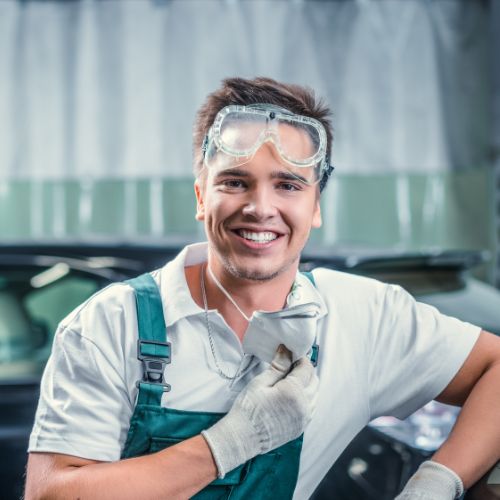 a man in a car repair shop smiling