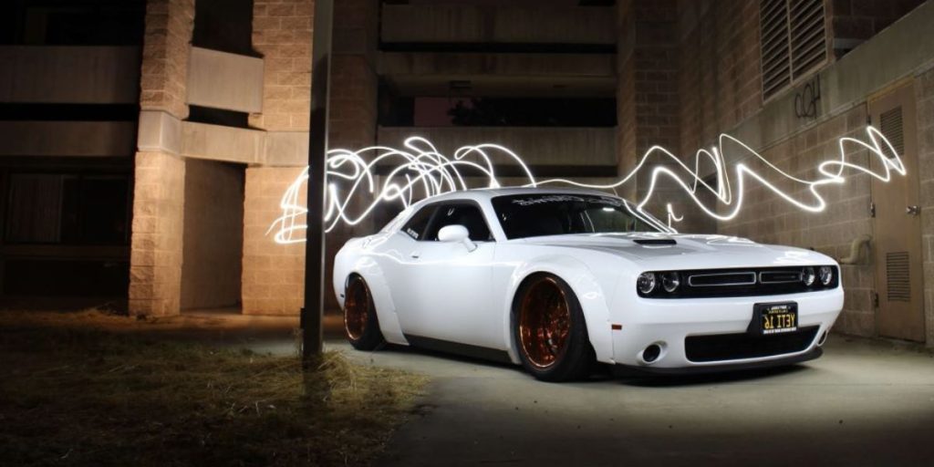 a white dodge challenger parked in front of a building
