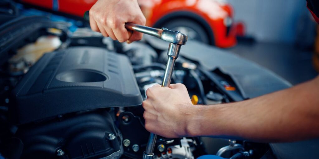 a man is holding a wrench while working on a car engine