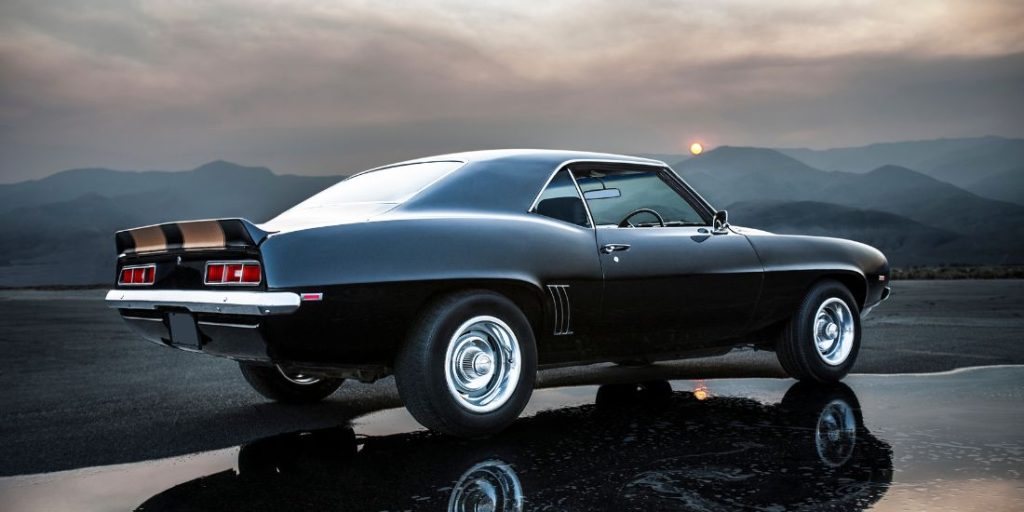 a classic muscle car parked on a wet road