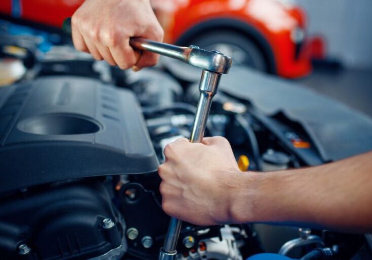 a man is holding a wrench while working on a car engine
