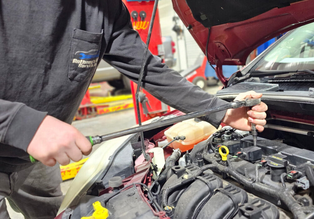 a man is holding a wrench while working on a car engine