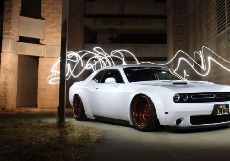 a white dodge challenger parked in front of a building